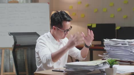 asian man having headache while working hard with documents at the office