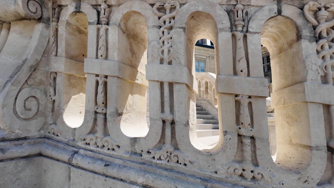 Vista al rallentatore attraverso la balaustra in pietra intagliata della Scalinata a Ferro di Cavallo, che rivela l'architettura storica del Castello di Fontainebleau in Francia
