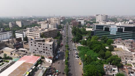 drone descends as cars drive on mall road in lahore, pakistan. urban cityscape