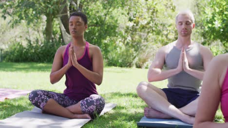 group of diverse young people meditating and practicing yoga together at the park