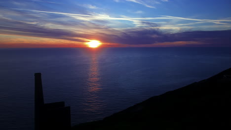 vista costera de una mina de cornualles mirando hacia una puesta de sol dorada