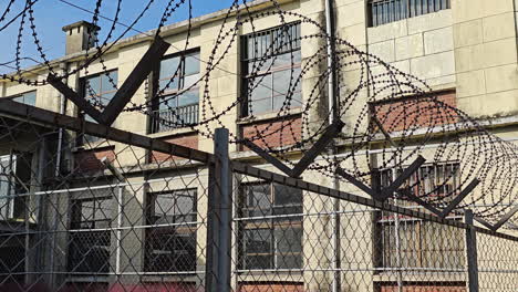 Spiral-Razor-Sharp-Prison-Barbed-Wire-Fence-Inside-Old-Prison-Yard---looking-up-closeup