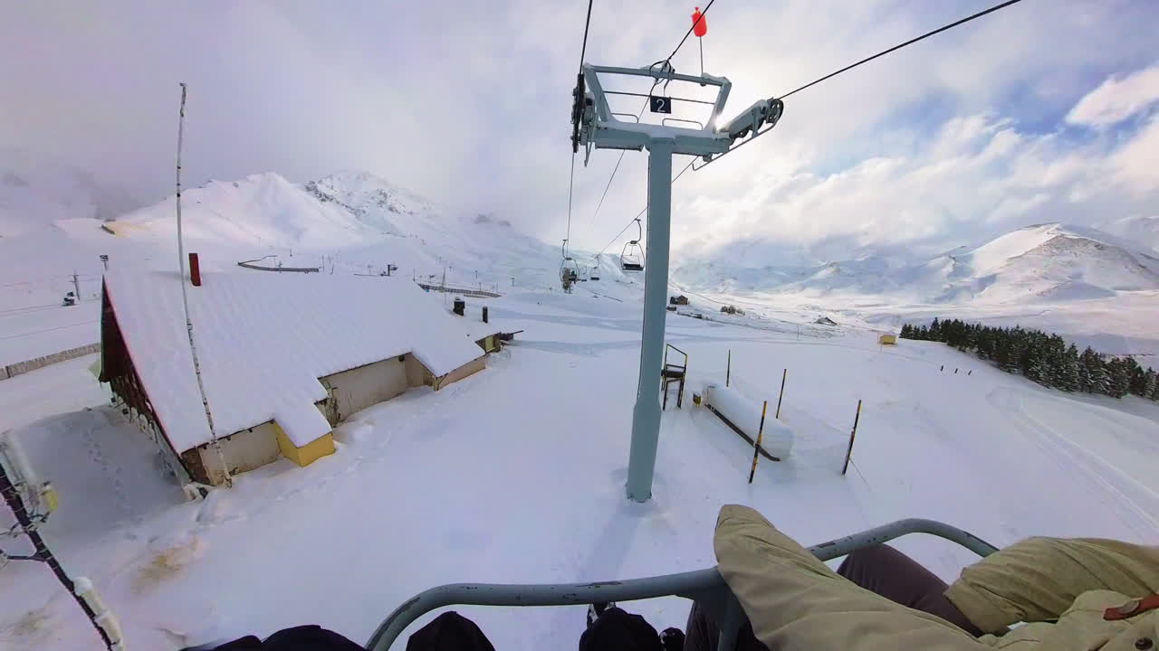 Tourist enjoying ski lift ride with panoramic snowy mountains in resort, Mendoza, Argentina, hyperlapse