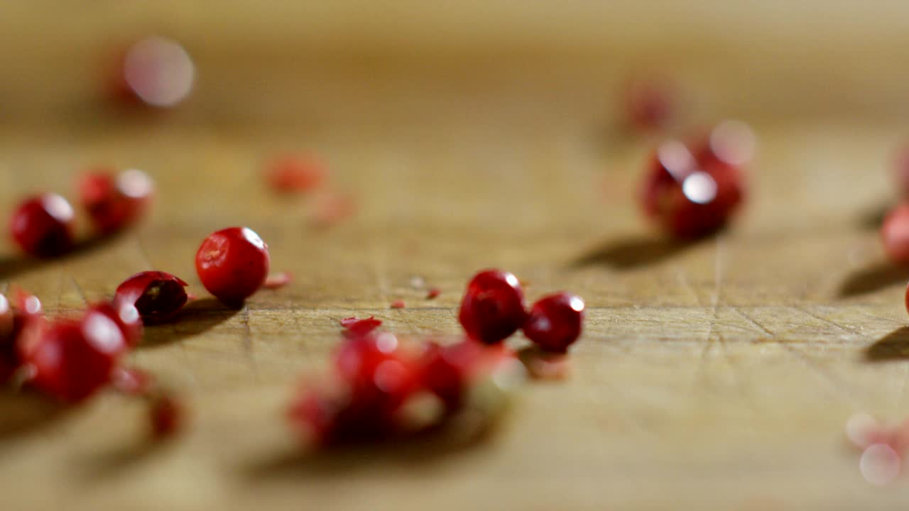 은 고추, 분홍색 고추의 곡물은 극심한 느린 속도로 나무 표면에 떨어지고 서로 여 있습니다.