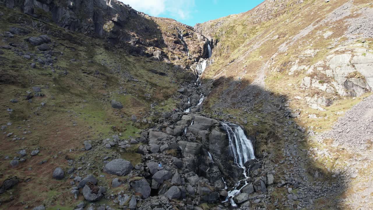 Tourists on rocks under the amazing Mahon Falls Comeragh Mountains Waterford Ireland cold winter afternoon