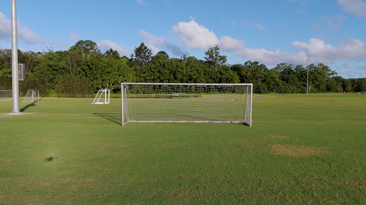 Drone, Açık Gökyüzü Altında Kale Direkleriyle Bir Futbol Sahasını Yakalıyor. Yeşil Çim, Parlak Aydınlatma ve Sabit Kamera Sakin Bir Atmosfer Yaratıyor