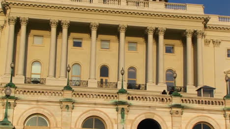 mirando hacia arriba desde la entrada del edificio del capitolio estadounidense y centrándose en las columnas del balcón de nivel medio y una puerta