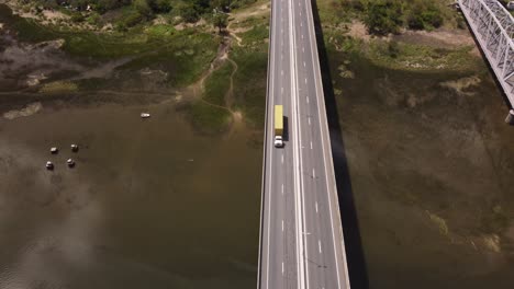 toma aérea de un camión amarillo conduciendo en el puente barra de santa lucía durante un día soleado en uruguay