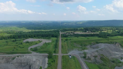 Drone flight above gravel pit quarry with water, sand piles, and access roads