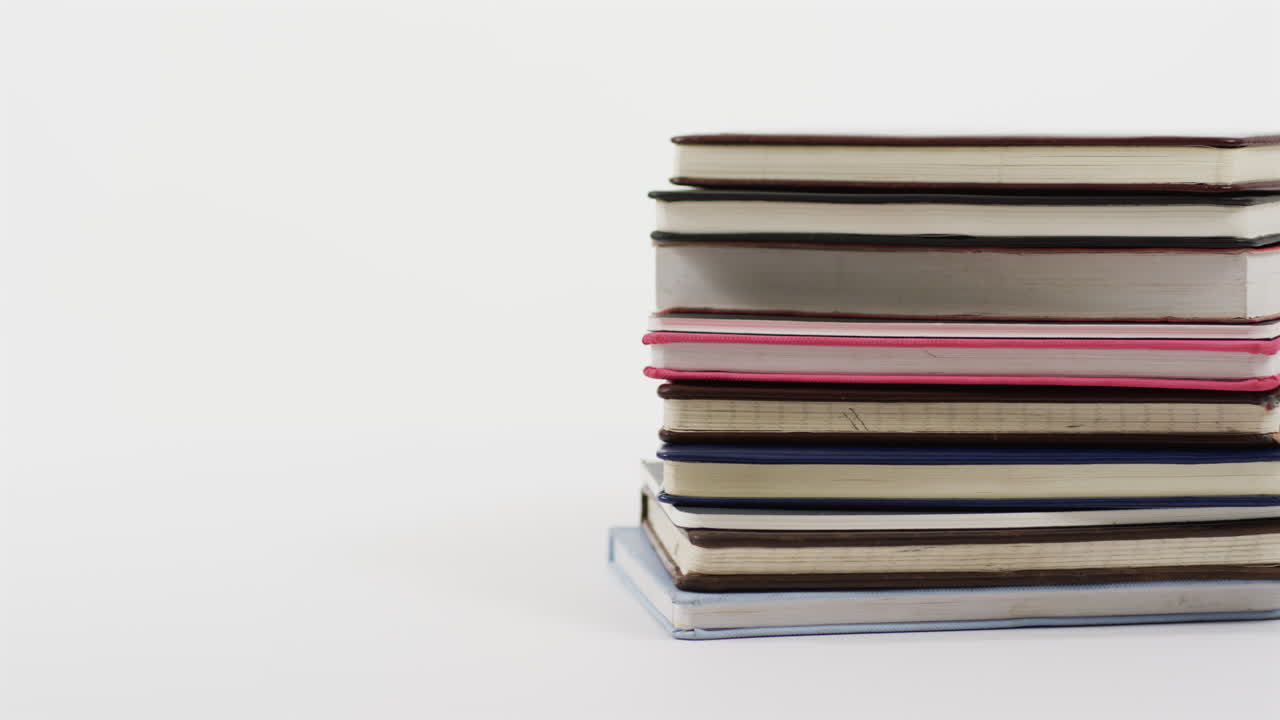 Close up of stack of books on white background, in slow motion
