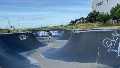 hombre montando patineta surfskate en una piscina de skate asfáltica en estoril, pdg, portugal