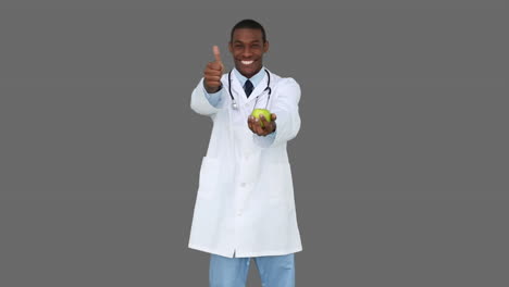 Happy-young-doctor-showing-camera-an-apple