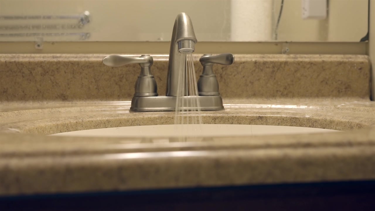Riparazione idraulica di uno scarico intasato del lavandino del bagno sotto il mobile.