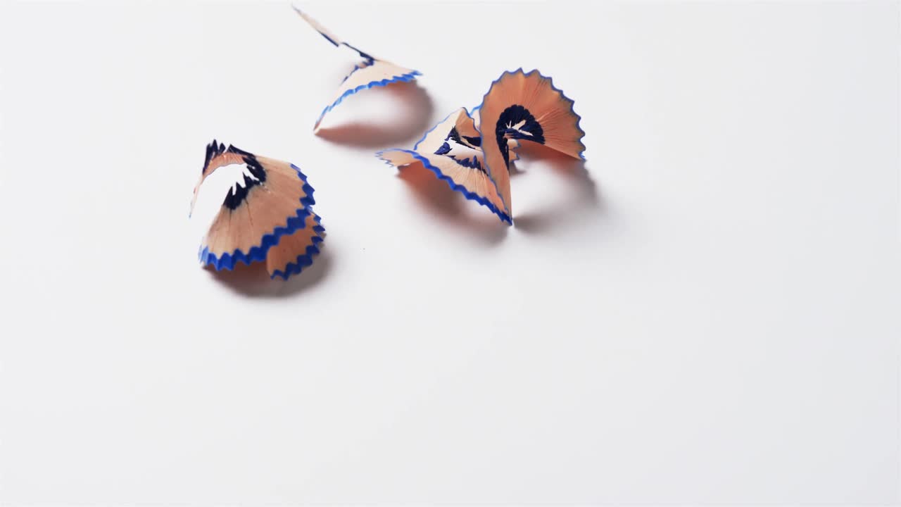 primer plano de virutas de lápiz azul con espacio de copia sobre fondo blanco, en cámara lenta