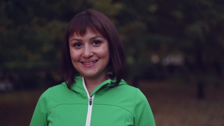 Donna in giacca verde in un parco autunnale