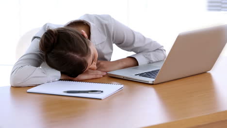 una mujer de negocios durmiendo en su escritorio.