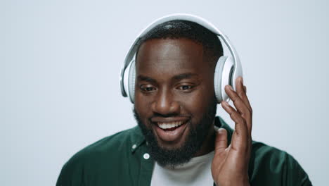 portrait of positive african man listening music on earphones in studio.