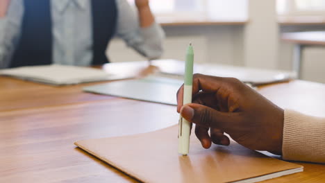 nahaufnahme einer hand eines mannes, der einen stift auf einem dokument auf dem tisch hält