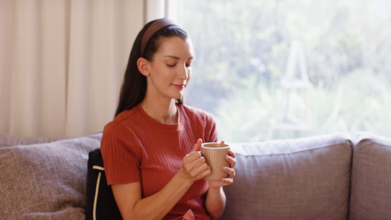 Young woman relaxing on sofa at home, enjoying peaceful afternoon indoors