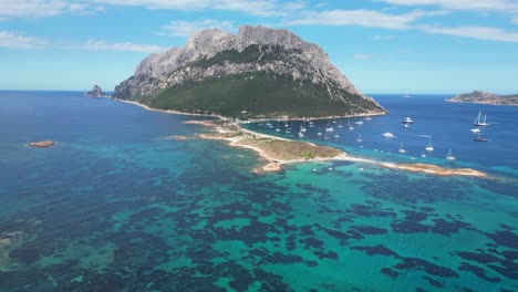 isla tavolara rodeada de barcos y mar azul turquesa durante el verano en cerdeña, italia - 4k aéreo
