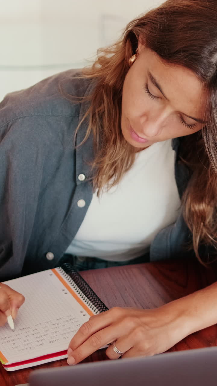 Giovane donna che prende appunti su un quaderno mentre studia