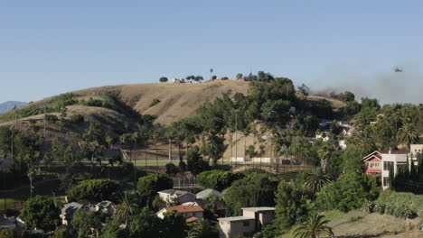 california bush fire in eastern los angeles city suburb, helicopter water drop