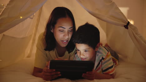 mother and son enjoying tablet time in a tent