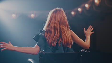 happy handicapped actress speaking on stage zoon out view of delighted woman on wheelchair talking to audience and gesticulating during performance on stage in theater