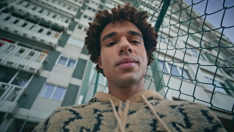 portrait latin guy looking camera in front high residential building. man posing