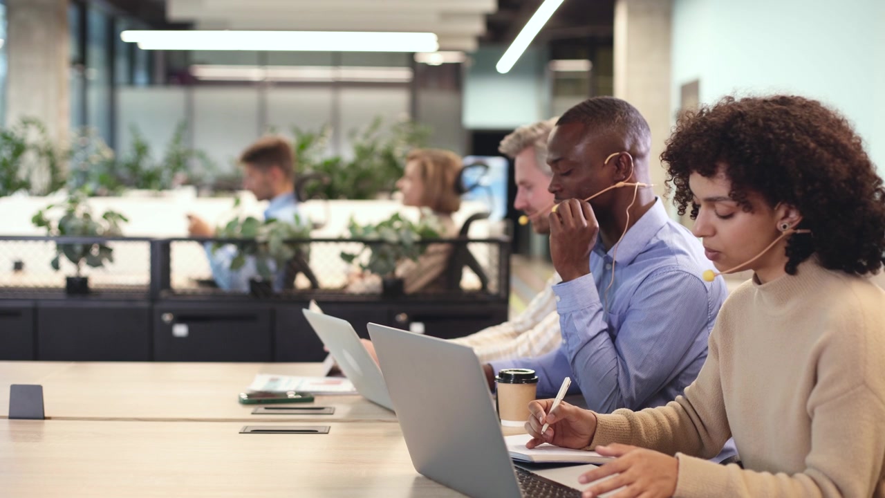 Mangfoldigt callcenter-team arbejder med laptops og headsets på moderne kontor