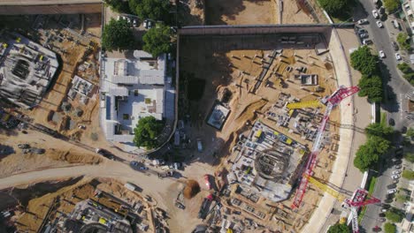 top down over tower crane in construction site on a big square - drone shot slie to left in tel aviv, israel