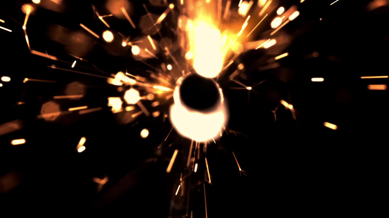 Scintille dorate luminose che volano su uno sfondo nero scuro.