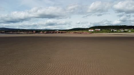 low flying drone shot over waterside beach heading towards shore by bay of fundy, new brunswick