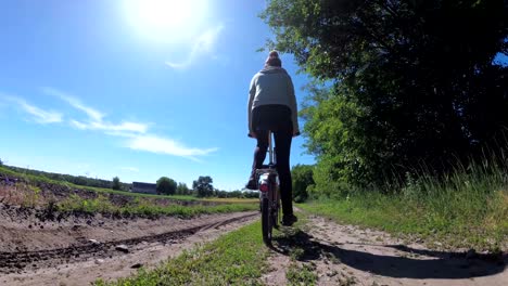 una mujer joven montando una bicicleta de época a lo largo de una carretera rural en un pueblo