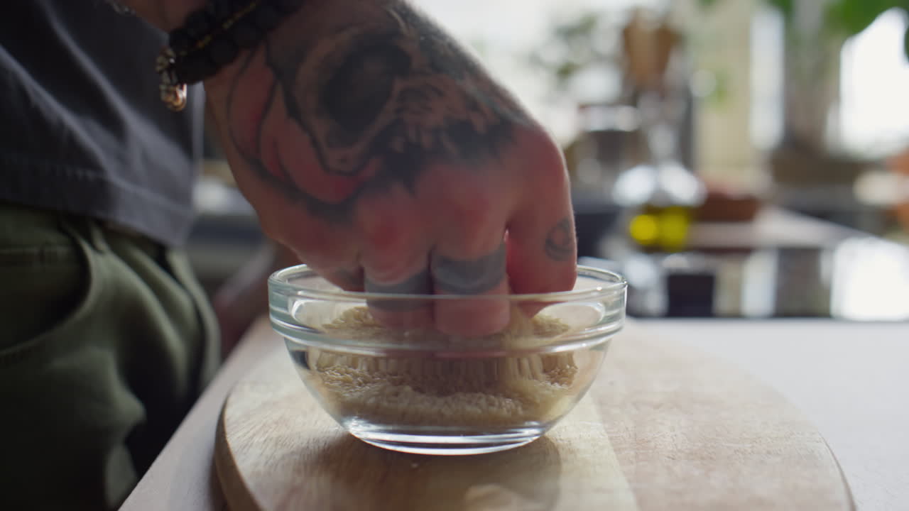 Hand of Chef Taking Sesame Seeds from Bowl