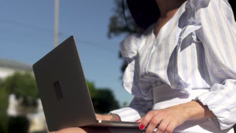 stylish woman typing on laptop in park