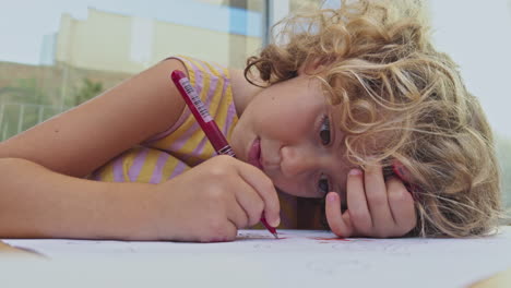 niño pequeño usando bolígrafos de colores y papel dibujando imágenes