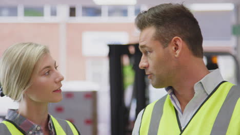 male manager in logistics distribution warehouse talking with female worker