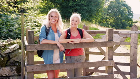 slow motion portrait of senior mother with adult daughter hiking in lake district uk looking over wooden gate