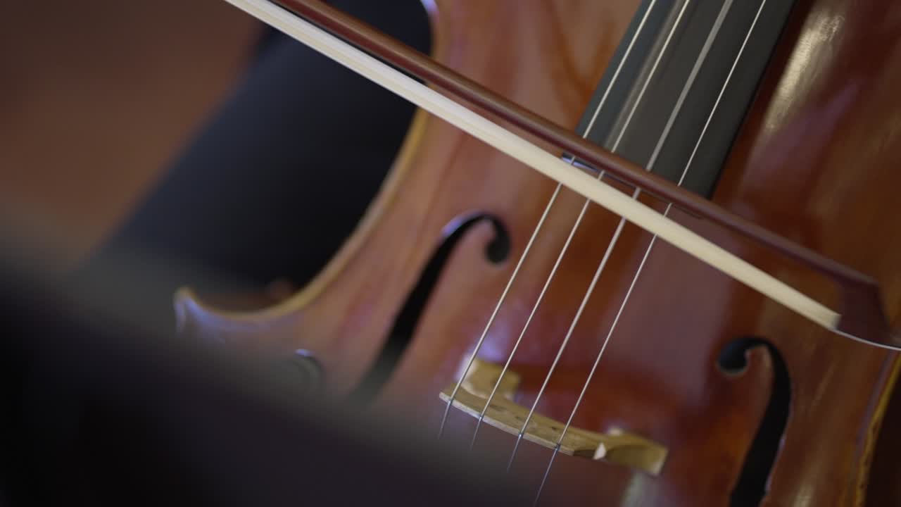 cello being played with a bow showing smooth motion and warm wood tones