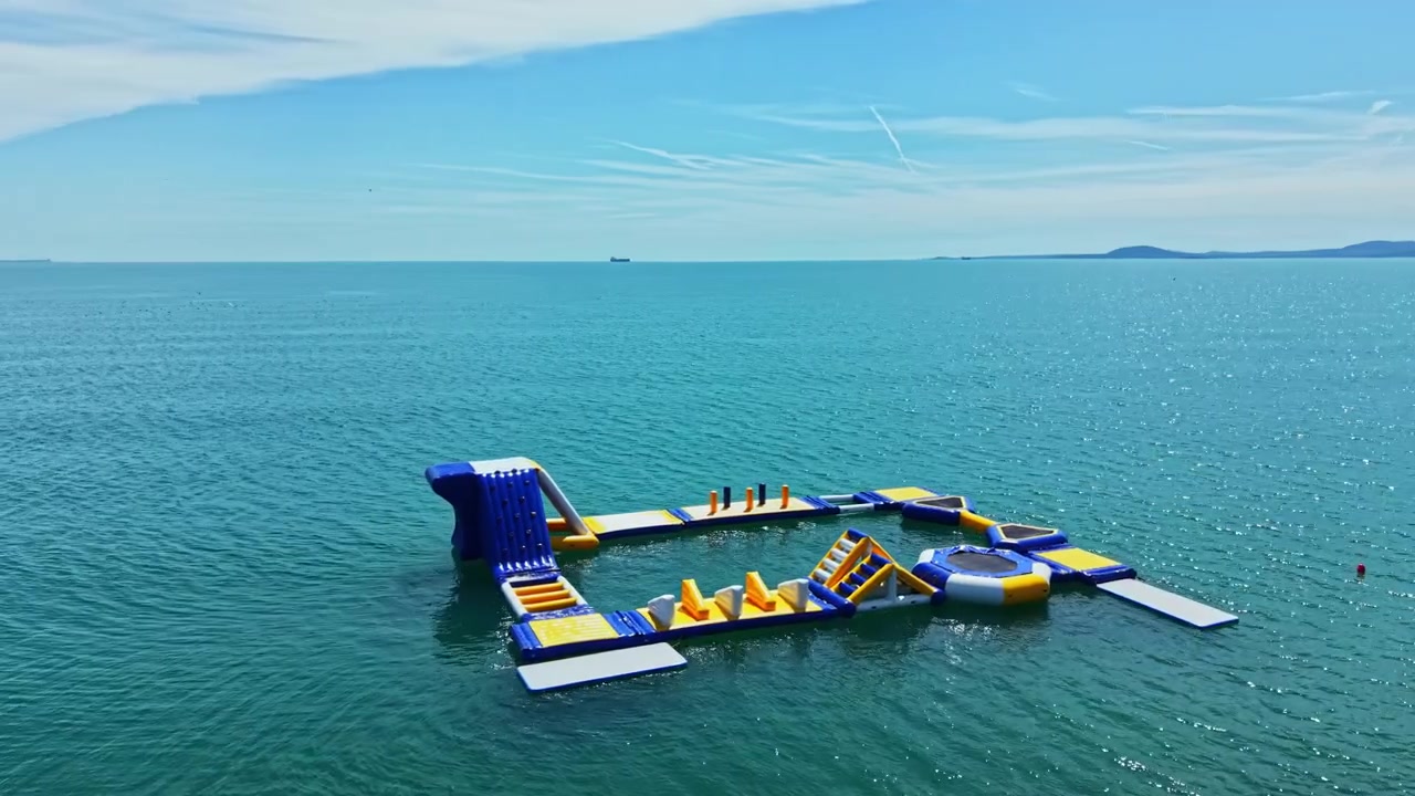 Water activity park located in the sea with various large inflatable structures on a clear day