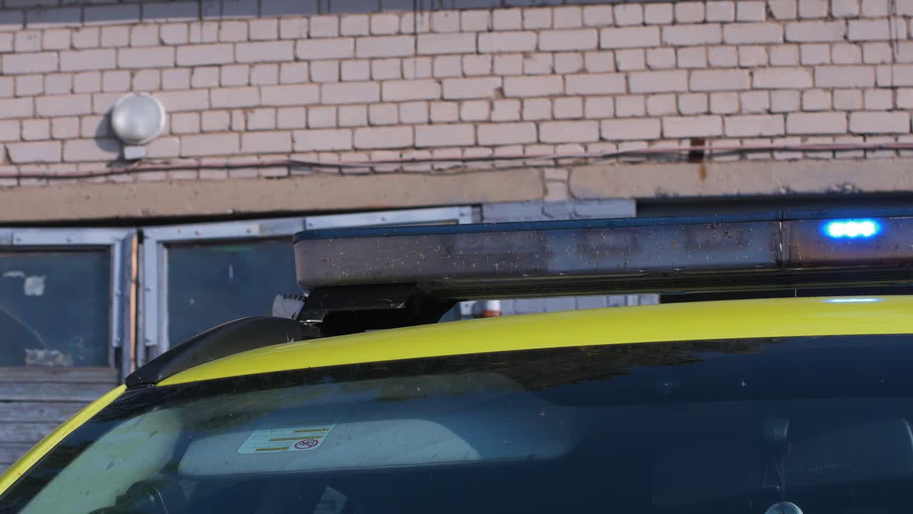 차고 밖에 주차된 노란색 구급대원 구급차 지붕, 파란색 깜박이는 경고등, 화창한 날, 중간 클로즈업 샷