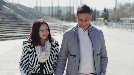 Happy-young-couple-holding-hands-together-during-stroll