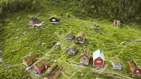 cabañas rústicas situadas en la ladera de una montaña verde y exuberante en rakssetra, noruega