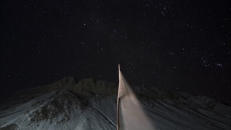 Nightsky-Time-lapse-of-Kaza-town-and-a-white-flag-in-the-foreground-at-the-height-of-12500ft-above-sea-level-in-Kaza,-Spiti-Valley,-Himachal-Pradesh-shot-in-4k