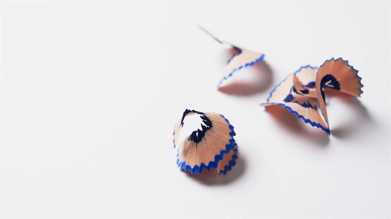 primer plano de virutas de lápiz azul con espacio de copia sobre fondo blanco, en cámara lenta