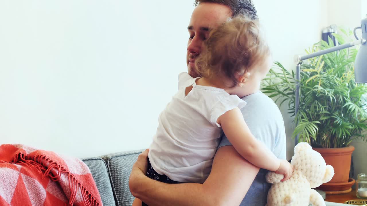 padre abrazando a su bebé en la sala de estar 4k
