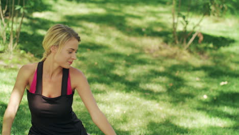 mujer sonriente estirando las piernas antes del gimnasio en el parque. mujer de fitness