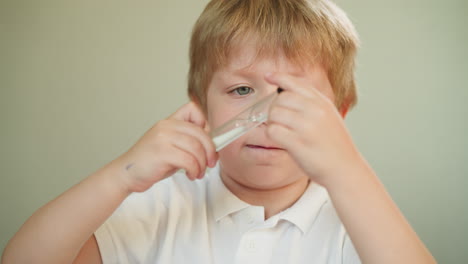 curious little blond boy looks at hourglass in children room