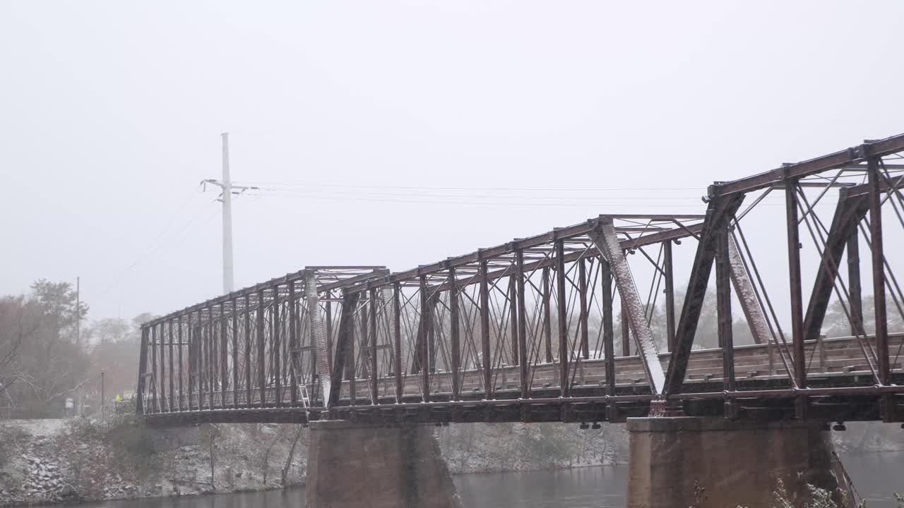 오클레어 위스콘신의 피닉스 공원에 있는 오래된 나무와 강철 철교는 신선한 눈이 내리는 동안 눈 덮인 다리를 얻고 치페와 강을 건너고 있습니다.